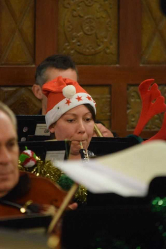 dark haired woman wearing a santa hat and playing the oboe