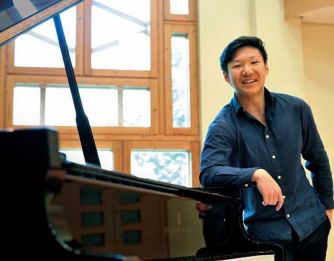 Noah Zhou leaning on piano