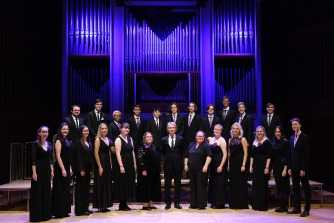 The 24 standing on stage in a group in concert dress The 24 standing on stage in a group in concert dress