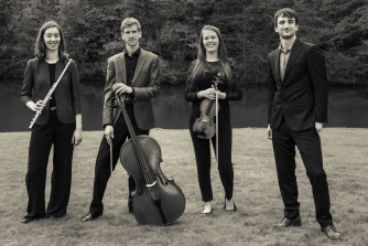 Members of Pocket Sinfonia standing holding flute, violin and cello Members of Pocket Sinfonia standing holding flute, violin and cello